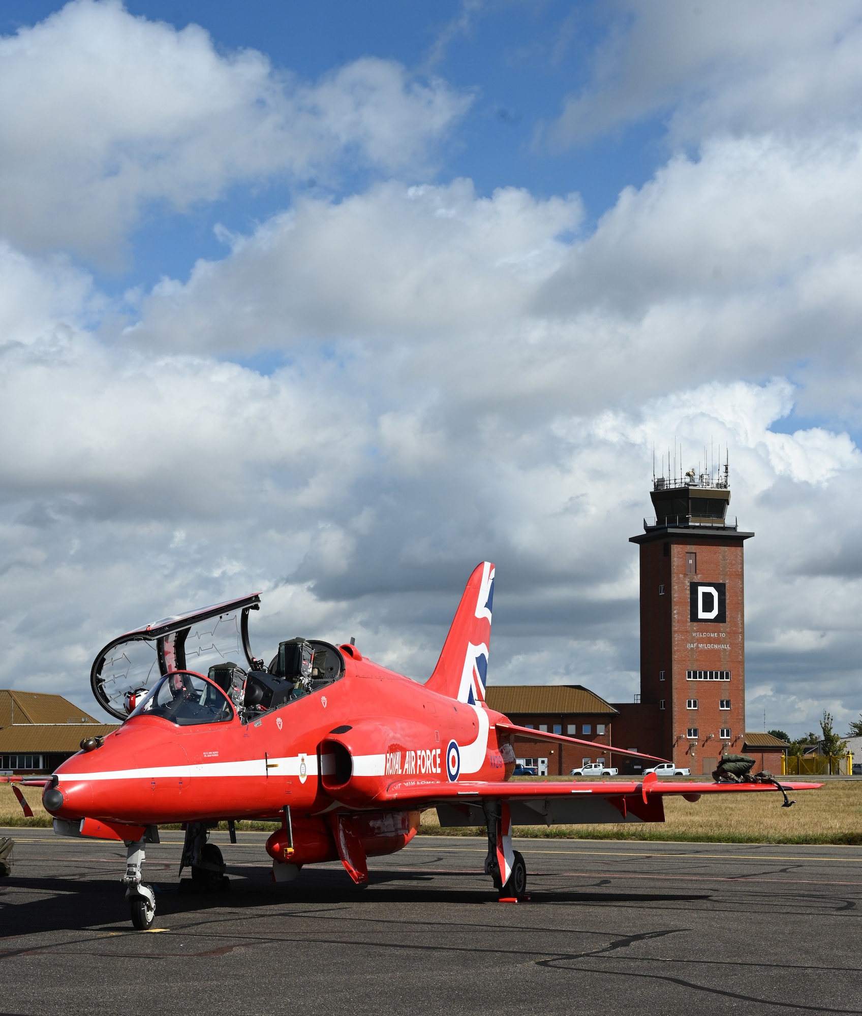 A Royal Air Force Hawk T1 aircraft from the RAF Aerobatic Team, the Red Arrows, sits in front of the air traffic control tower ready to be refueled after performing an aerial demonstration at RAF Mildenhall, England, Aug. 28, 2026. The Red Arrows perform a combination of close formations and precision flying, and have been performing since 1965. (U.S. Air Force photo by Karen Abeyasekere)