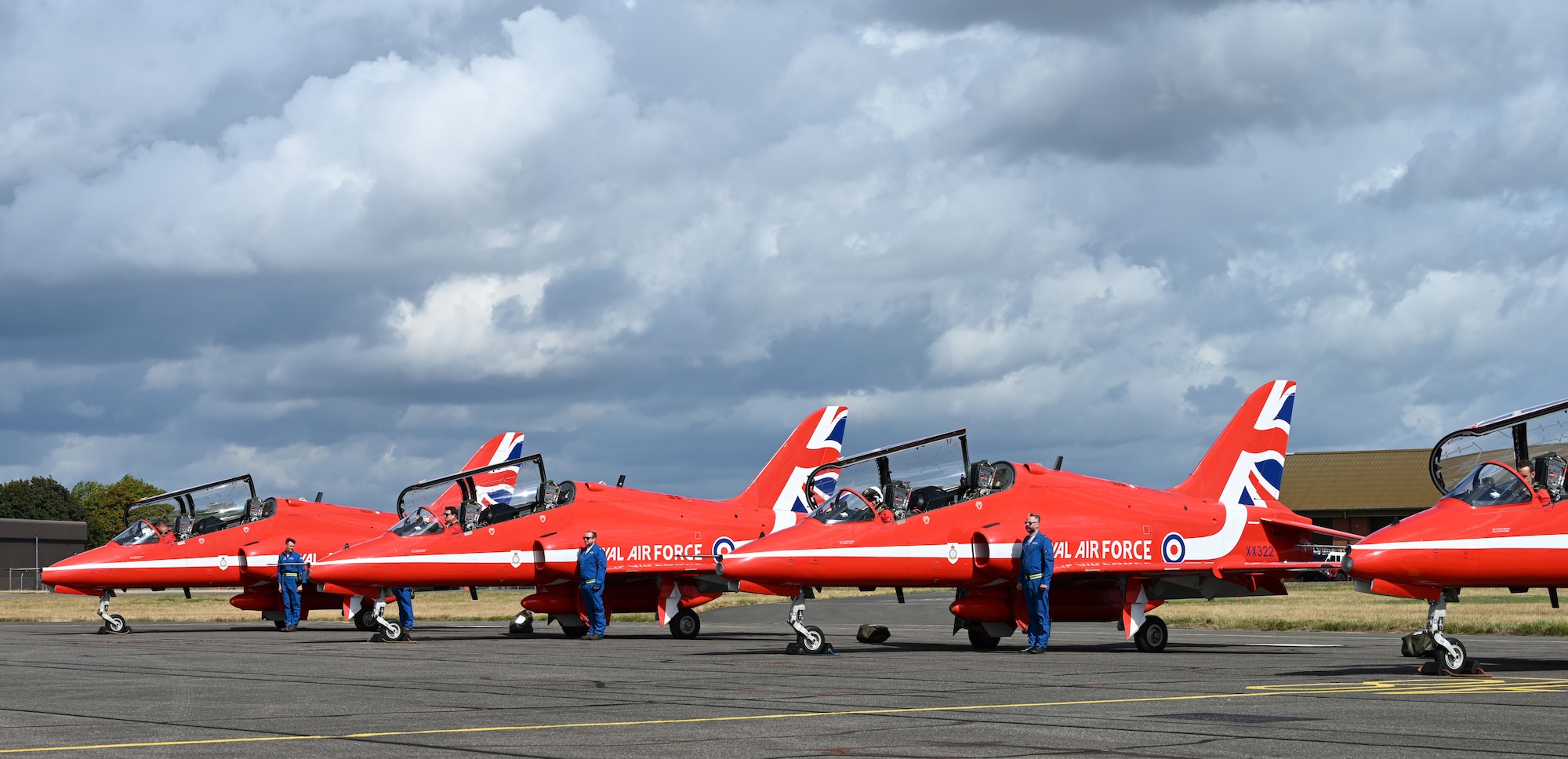 Members of “Circus,” the traveling support crew of the Royal Air Force Aerobatic Team, the Red Arrows, stand ready by the Hawk T1 aircraft to show they are in-place and ready to carry out their vital checks of the aircraft at RAF Mildenhall, England, Aug. 28, 2026. The Circus support crew – known as Circus 1 to 11, denoting which pilot they fly with – are hand-picked each year and fly in the rear seats of the jets during the season. (U.S. Air Force photo by Karen Abeyasekere)