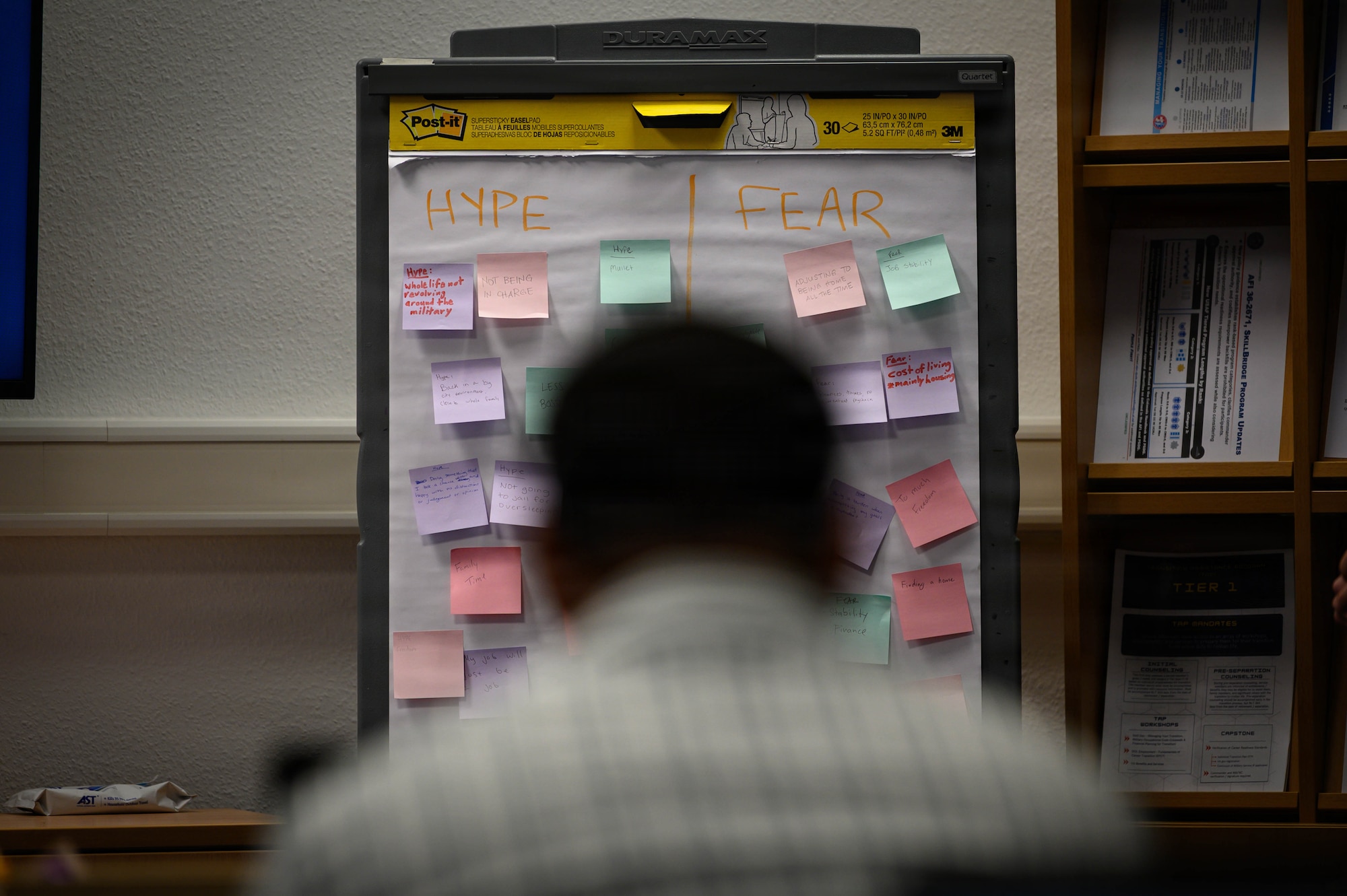 A man sits in front of a board with sticky notes on it.