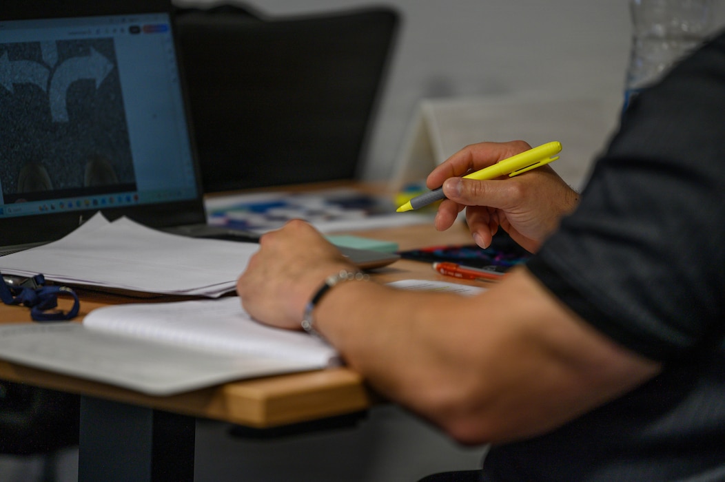 Papers rest on desk in front of a man holding a highlighter.