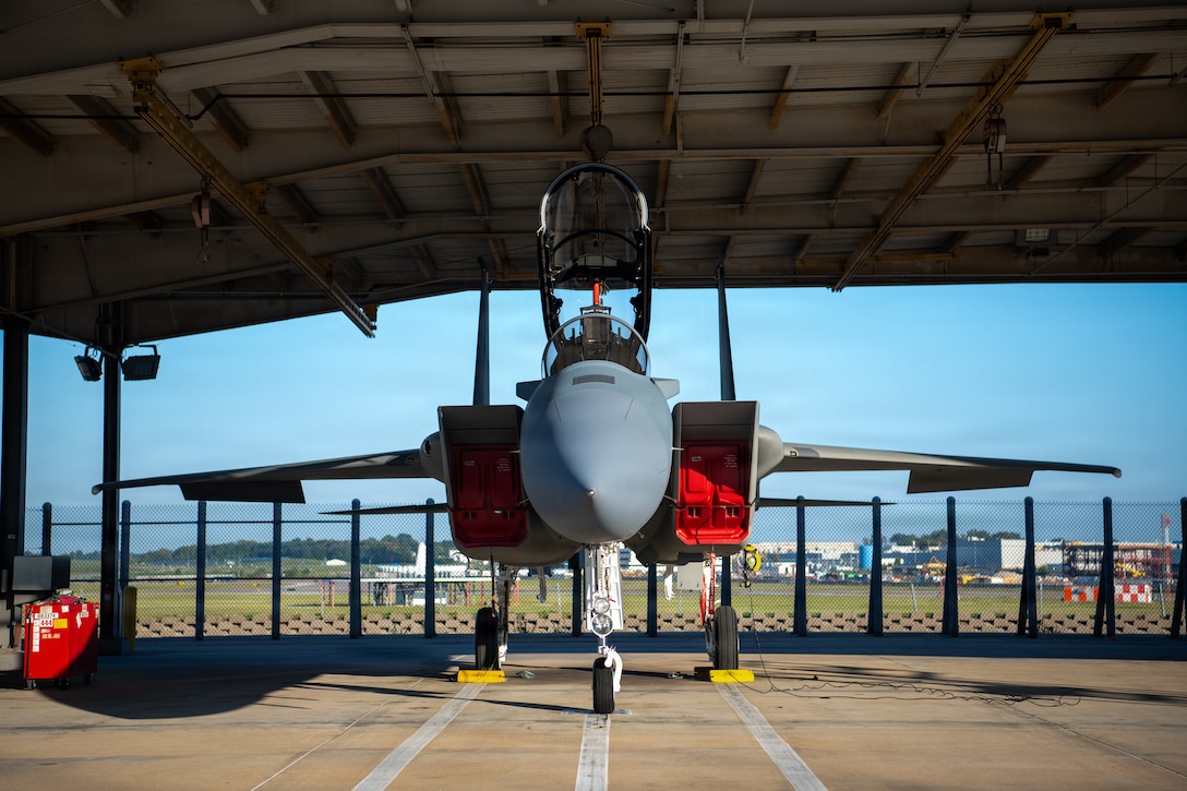 front view of the nose of a jet aircraft underneath a hangar