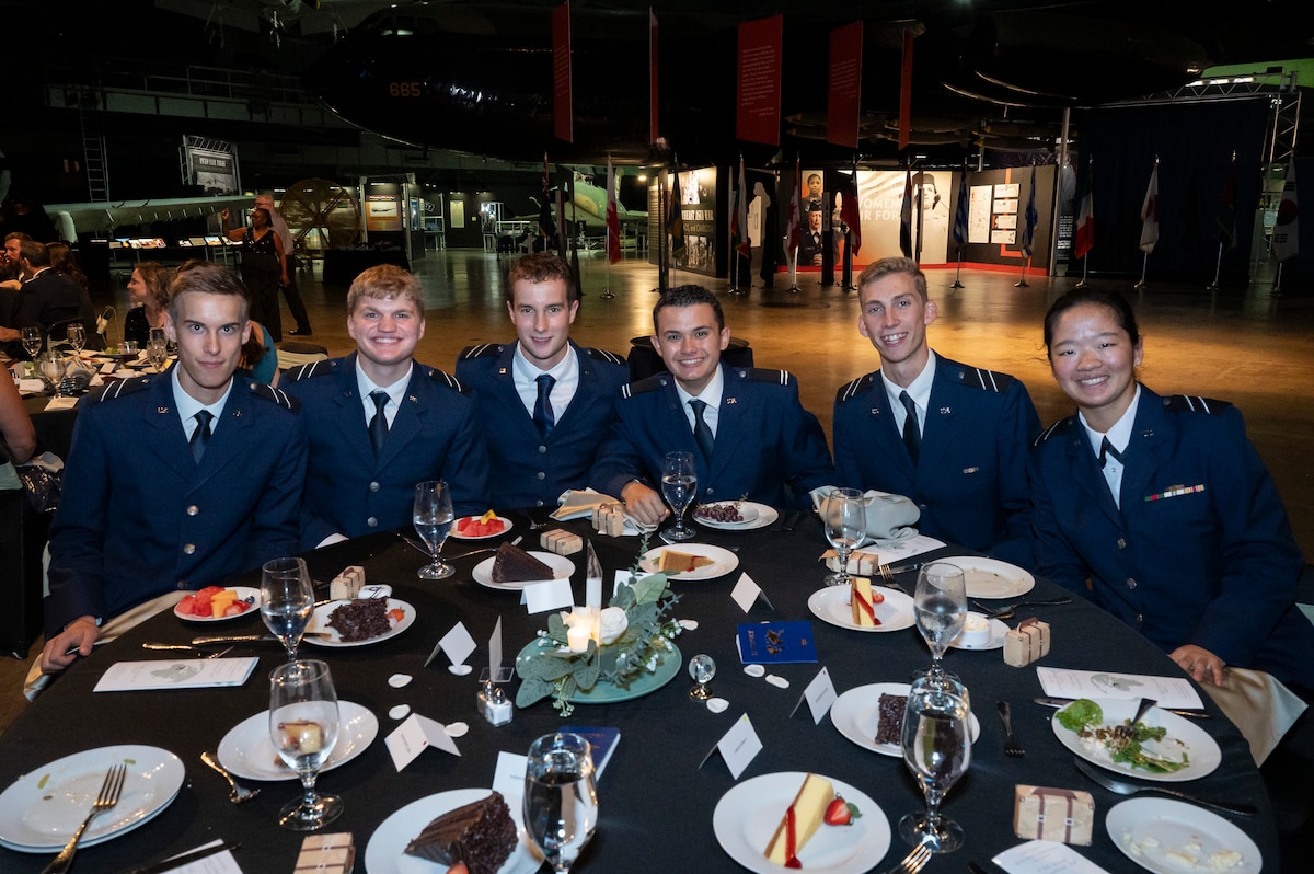 Young foreign officers in dress attire sit at round table and smile.
