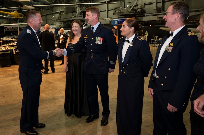 Men and women in formal Air Force attire stand and talk.