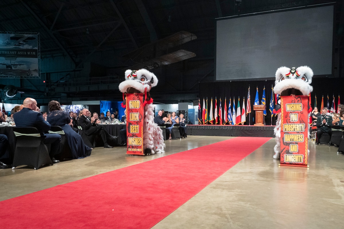People wearing dragon suits dance at international ball. There is a red carpet in the shot.