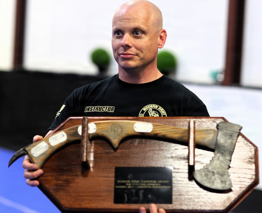 Modern Army Combatives instructor Sgt. 1st Class Steven Metzger holds the TAG Combatives Tournament Team Trophy.