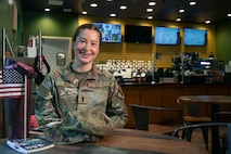Alt Text: A photo of a service member smiling while sitting inside of a coffee shop.