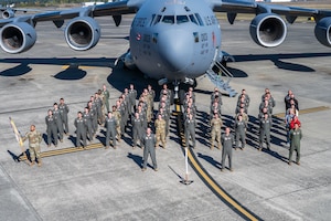 A group of people stand in formation in front of a plane.