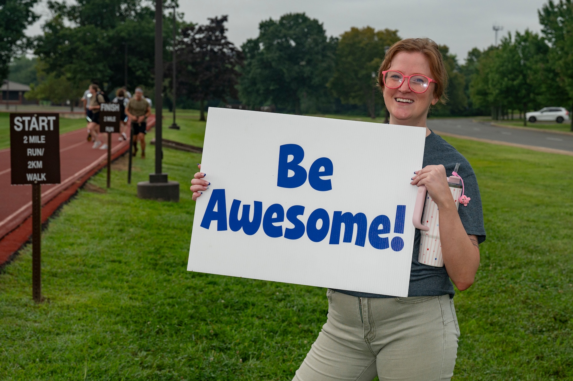 Susan Franco, 87th Air Base Wing Integrated Prevention and Resilience Office prevention coordinator, holds a sign to motivate 5K run and ruck participants during Comprehensive Fitness Day at Joint Base McGuire-Dix-Lakehurst, N.J., Aug. 28, 2026.