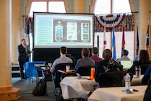 Attendees of the Digital Transformation in Metrology Workshop listen to a brief from Robert E. Fritzsche, metrology and calibration chief engineer at Naval Surface Warfare Center (NSWC) Corona Division, at the Lake Norconian Conference Center in Norco, Calif., May 18, 2026. The landmark international workshop brought together over 80 experts from the Department of War, other U.S. federal agencies, industry, and partner nations to forge a path towards a shared, secure, and standardized international digital infrastructure for measurement data.