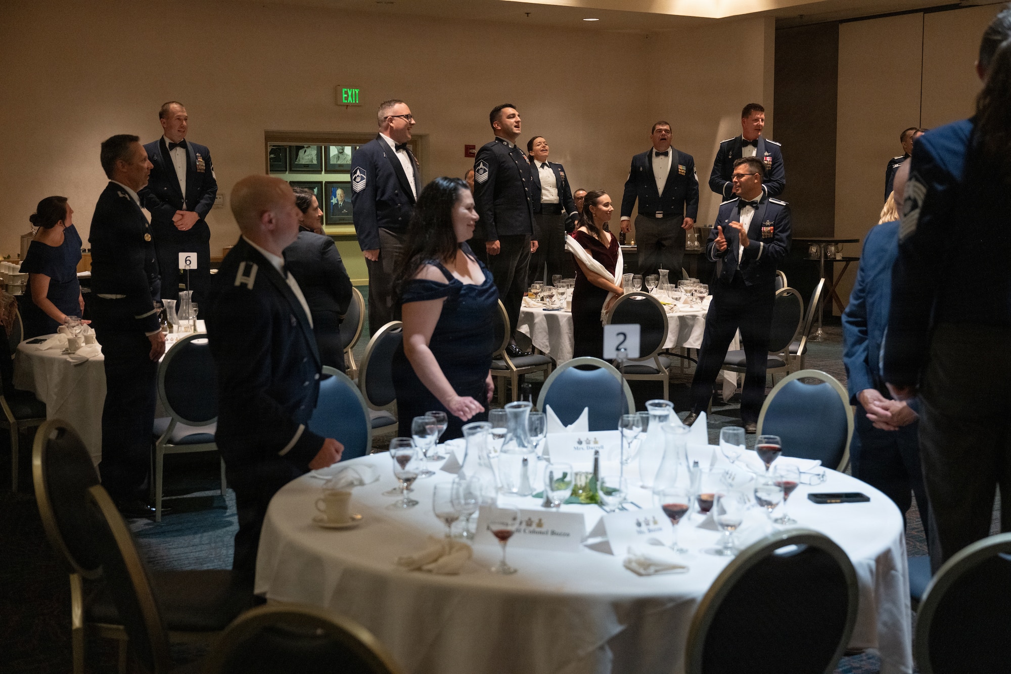 Servicemembers stand on chairs and sing.