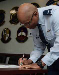 A man in an Air Force uniform is signing a proclamation poster.