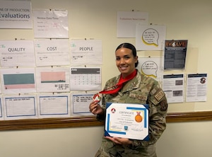 Senior Master Sgt. Antigone Trimble stands in front of the 459th Force Support Squadron’s Evaluations Gemba board with her EVOLVE Bronze Certification, July 13, 2026, at Joint Base Andrews, Md. (U.S. Air Force photo by Senior Master Sgt. Jamie Serrano)