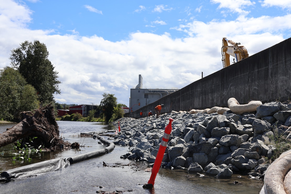 Photo of men in safety hats and vests repairing a levee