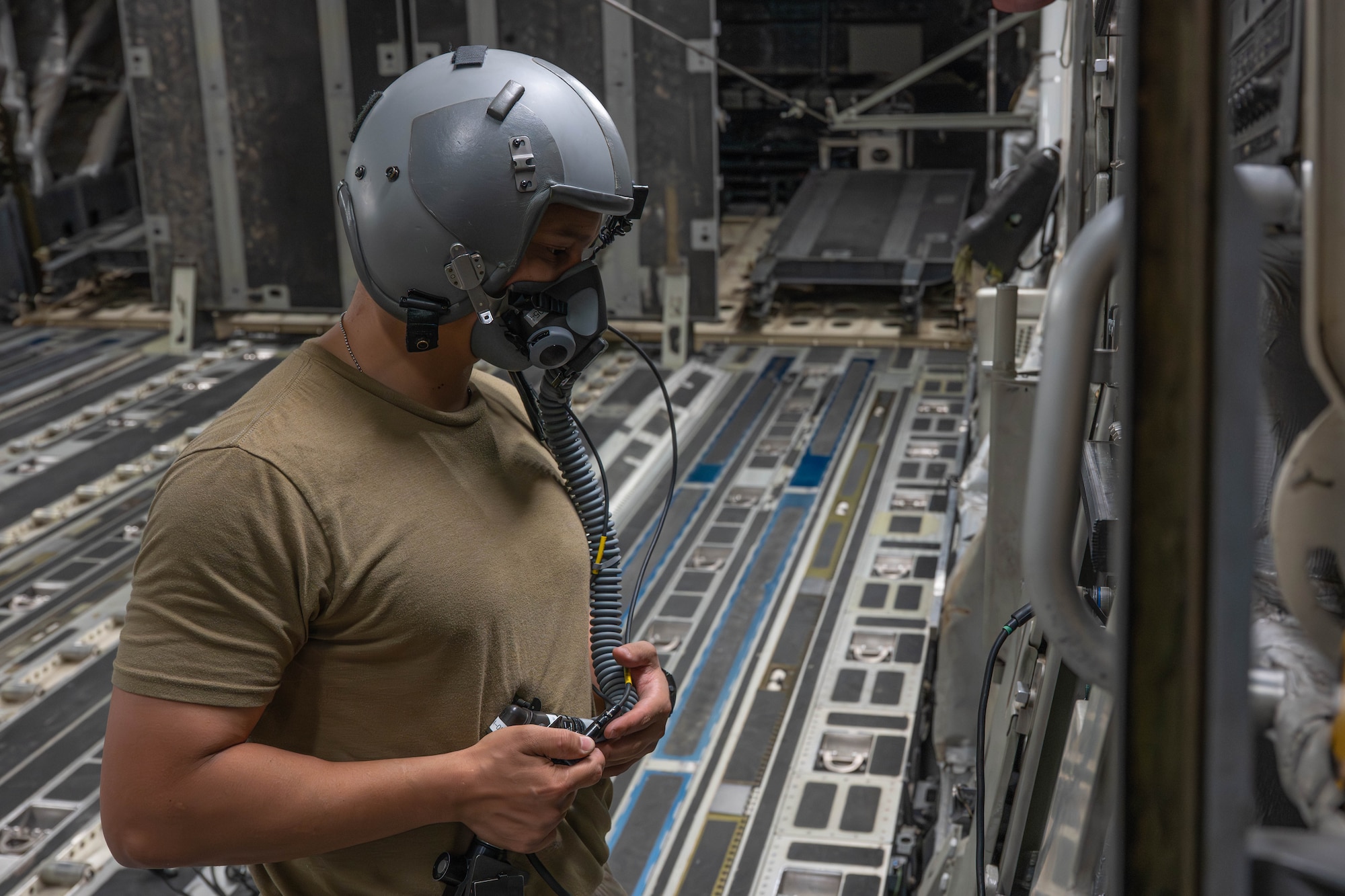 A man wears a helmet and oxygen mask aboard an aircraft.