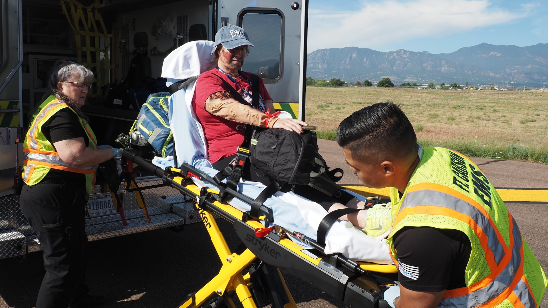 Heidi Romero, a paramedic supervisor with Fort Carson Emergency Medical Services, and Private 1st Class Oziel Lara, a 68w Combat Medic assigned to the Evans Army Community Hospital Department of Emergency Services, load an exercise casualty volunteer into an ambulance during a full-scale Mass Casualty exercise simulating a commercial aircraft crash at the Colorado Springs Airport Aug. 19, 2026.