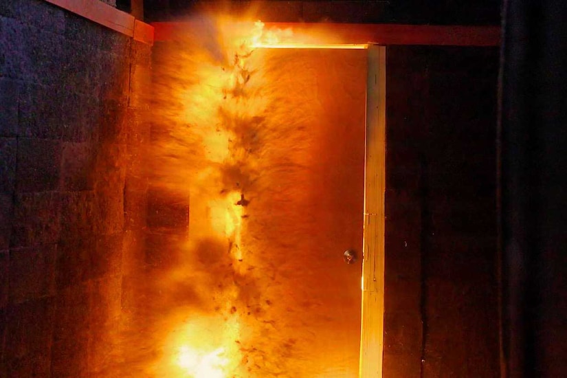 A door in a dark room is surrounded by fire piercing through the cracks.
