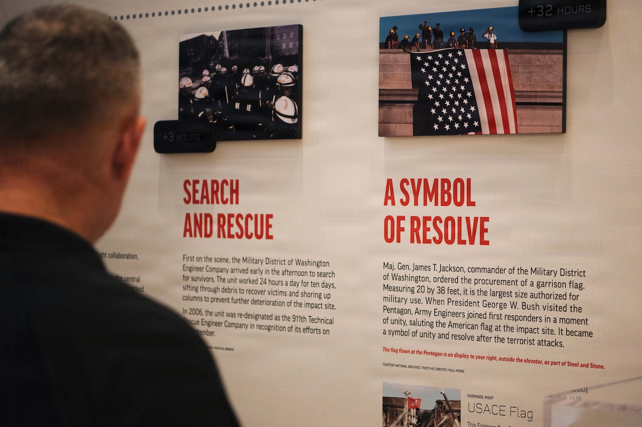 A person looks at an exhibit on a wall that has a photo of the Pentagon with a flag draped over it and the words "A Symbol of Resolve" and "Search and Rescue" in large red type.