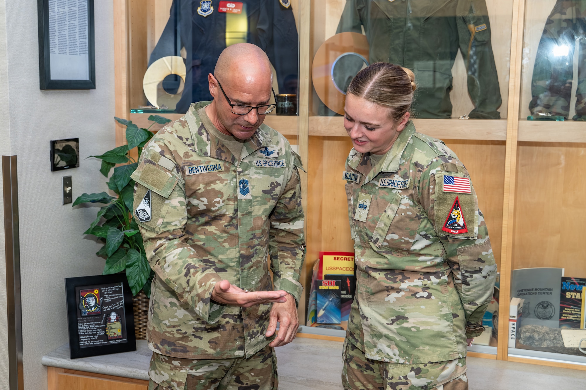 Chief Master Sgt. of the Space Force John Bentivegna, left, presents a challenge coin to U.S. Space Force Spc. 4 Ashlynn Agaciewski, Space Delta 15 target analyst, right, during a visit to Schriever Space Force Base, Colorado, Sept. 1, 2026. Bentivegna engaged with Guardians during his visit to the National Space Defense Center to hear firsthand about their experiences and the missions they support. (U.S. Space Force photo by Dalton Prejeant)