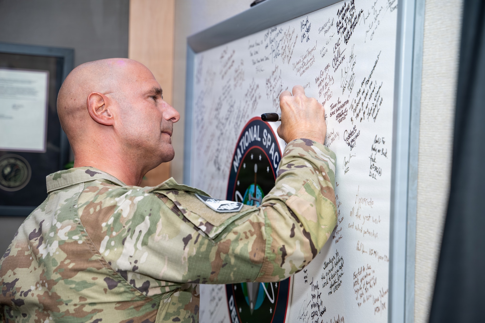 Chief Master Sgt. of the Space Force John Bentivegna signs the National Space Defense Center heritage board.