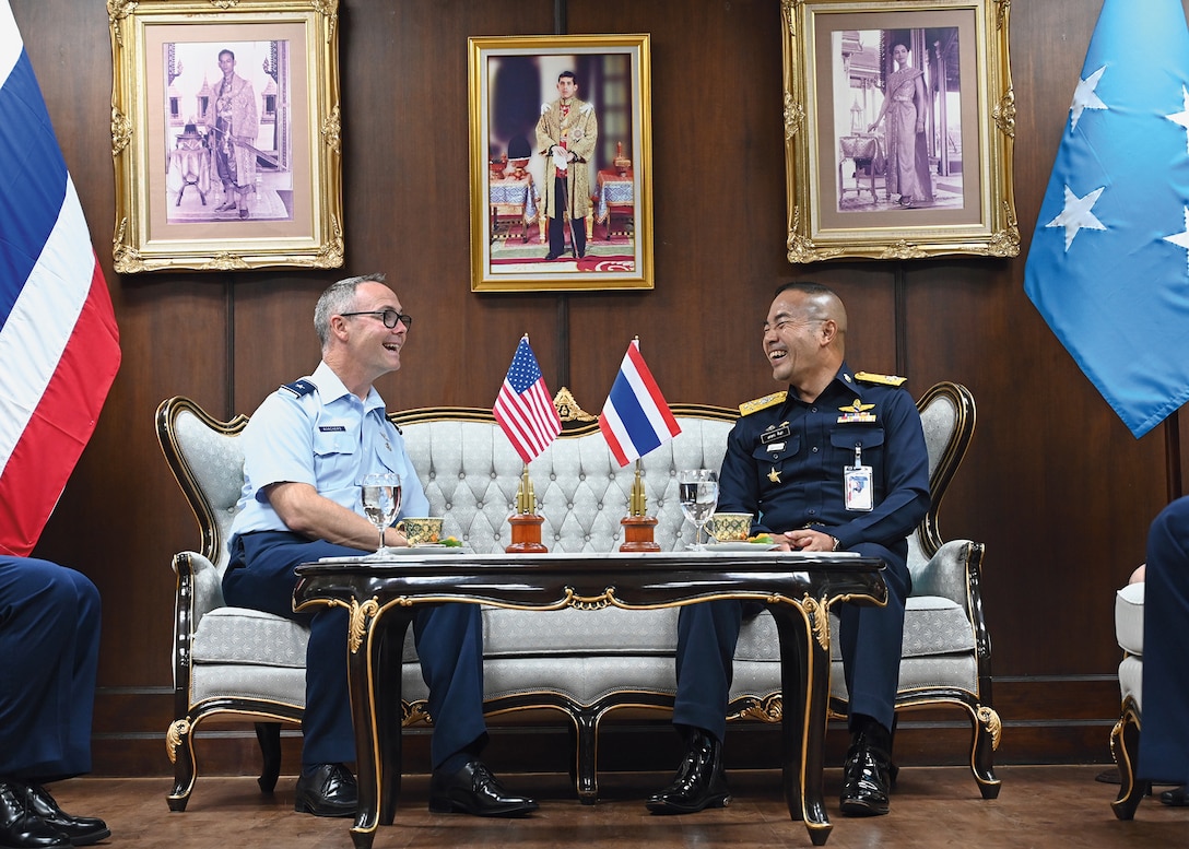 Two military men talk and laugh while sitting on the couch.