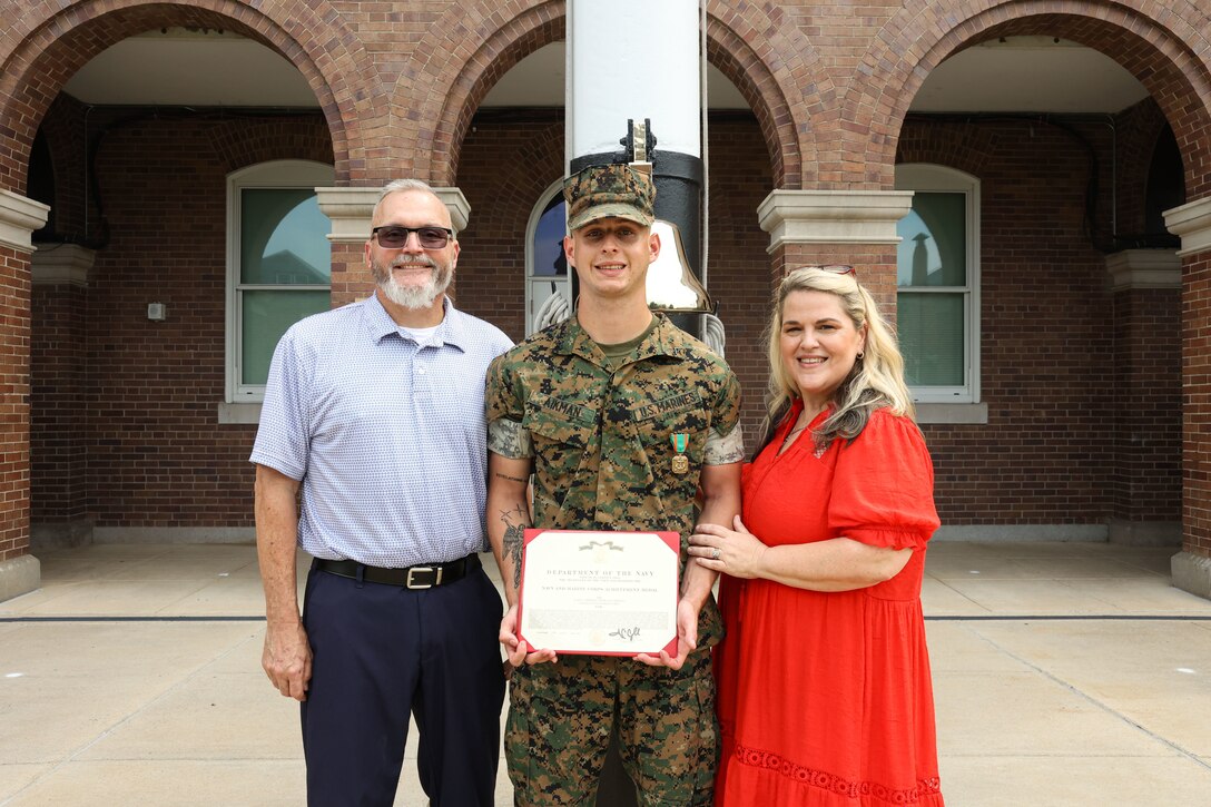 U.S. Marine Corps Lance Cpl. Joshua Aikman, a rifleman with Guard Company, Marine Barracks Washington, center, with his father, Kevin Aikman, left, and step-mother, Rhonda Aikman, right, pose for a photo after receiving the Navy and Marine Corps Achievement Medal during an award ceremony at Marine Barracks Washington, D.C., Sept. 3, 2026. The Marines were awarded for their decisive actions as part of a reaction team that safely neutralized an armed threat on the installation. (U.S. Marine Corps photo by Cpl. Brynn L. Bouchard)