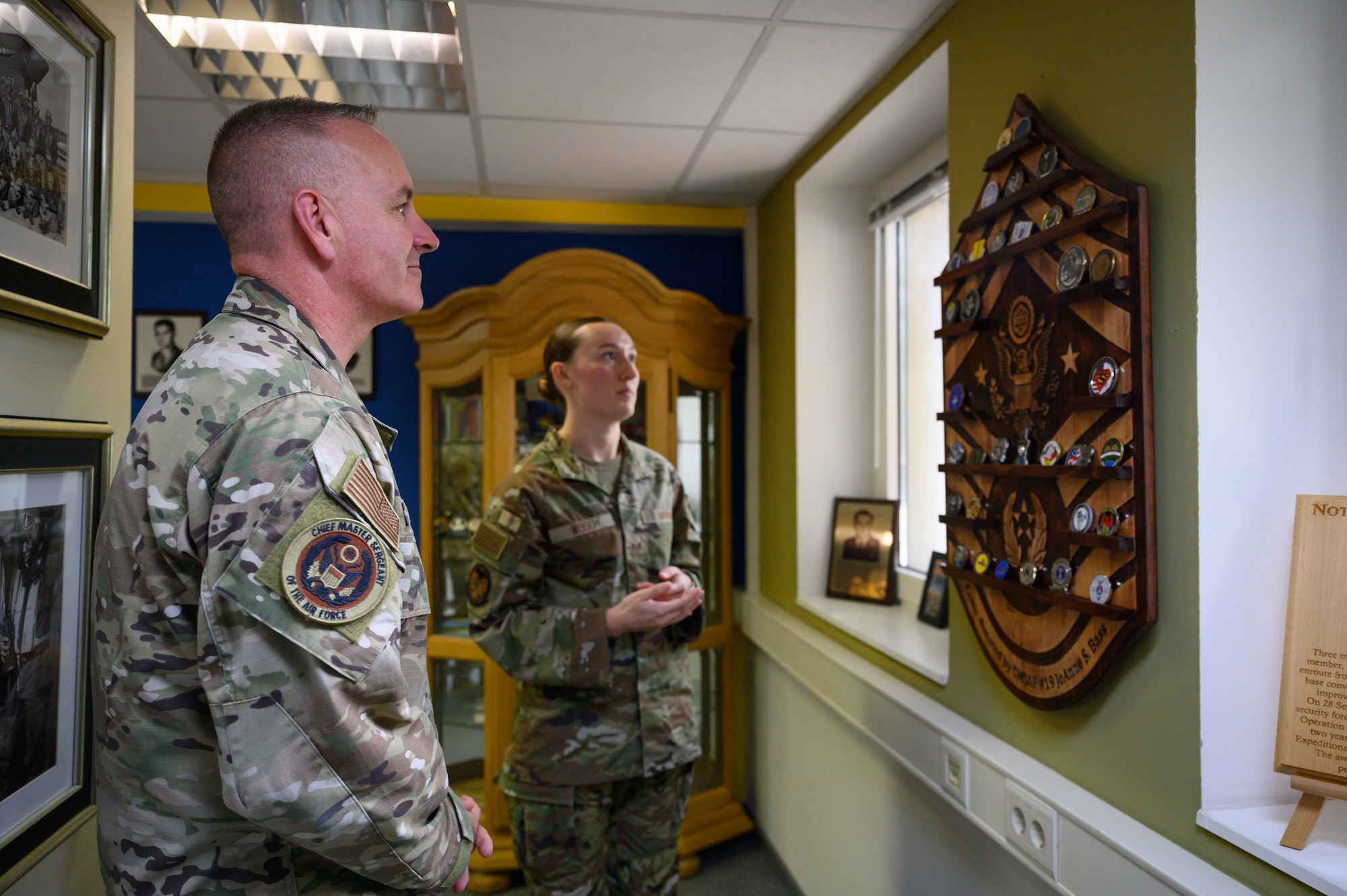 Chief Master Sergeant of the Air Force David Wolfe, left, speaks with Staff Sgt. Evelyn Wood, 52nd Force Support Squadron Airman Leadership School cadre, about a display of challenge coins during a tour of the Pitsenbarger Airman Leadership School Heritage Hall.