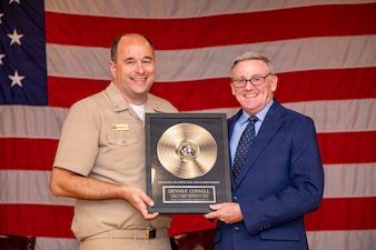 Cmdr. Joseph Fromknecht, a deputy chief of staff assigned to Naval Medical Forces Atlantic, presents Dennis Connell, a secretary with NMFL, and a native of Rensselaer, New York, with a retirement gift during Connell’s retirement ceremony aboard Naval Support Activity (NSA) Hampton Roads - Portsmouth Annex, Portsmouth, Virginia, Aug. 28, 2026. Connell retired from federal civil service following 41 years of combined military and federal civilian service. (U.S. Navy photo by Mass Communication Specialist 2nd Class Levi Decker)
