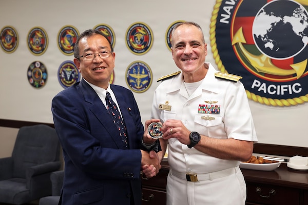 Rear Adm. Kevin Brown, commander of Naval Medical Forces Pacific, presents a command coin to Jun Tsushima, state minister of the Cabinet Office of Japan, during a Japanese delegation visit to NMFP headquarters, Aug. 25, 2026. The exchange highlighted ongoing bilateral cooperation between U.S. and Japanese medical services. (U.S. Navy photo by Arsenio R. Cortez Jr.)