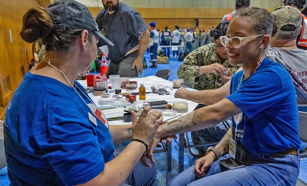 vATSUGI, Japan (Sept. 1, 2026) — An American Red Cross Yokosuka volunteer applies moulage to a role player during Big Rescue Kanagawa 2026 at the Kanagawa Prefectural Comprehensive Disaster Prevention Center and Fire Academy. Big Rescue Kanagawa is a large-scale, multi-agency disaster-response exercise jointly organized by Kanagawa Prefecture and Atsugi City to rehearse patient reception, bilateral triage, and emergency response operations. (U.S. Navy photo by Daniel Taylor/USNMRTC Yokosuka Public Affairs)