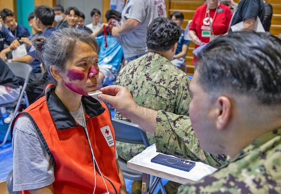 ATSUGI, Japan (Sept. 1, 2026) — A U.S. Navy hospital corpsman assigned to U.S. Navy Medicine Readiness and Training Command Yokosuka applies moulage, makeup used to simulate injuries, to an American Red Cross Yokosuka volunteer before Big Rescue Kanagawa 2026 at the Kanagawa Prefectural Comprehensive Disaster Prevention Center and Fire Academy. Big Rescue Kanagawa is a large-scale, multi-agency disaster-response exercise jointly organized by Kanagawa Prefecture and Atsugi City to rehearse patient reception, bilateral triage, and emergency response operations. (U.S. Navy photo by Daniel Taylor/USNMRTC Yokosuka Public Affairs)