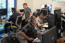 US military and civilians work on computers
