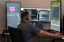 a man wearing a headset works on a computer