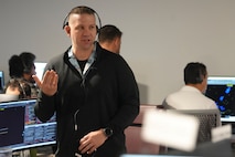 a man wearing a headset stands while speaking