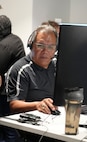 a man wearing a headset works on a computer