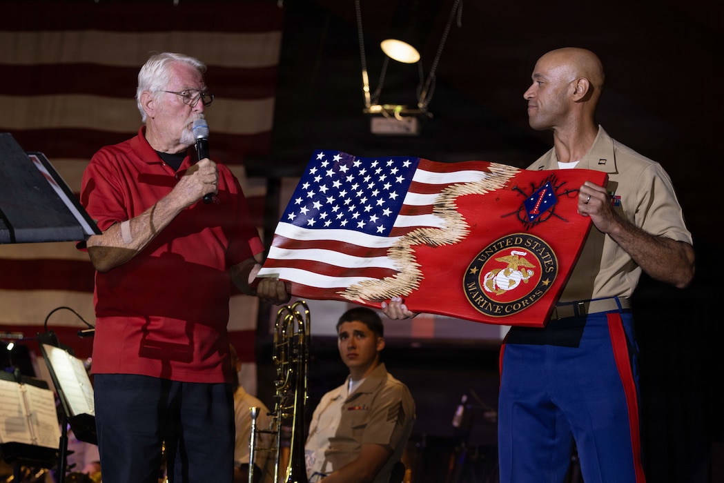 U.S. Marine Corps Capt. Eric Kyne, a band officer with the 1st Marine Division Band, receives a plaque from Ken Dahkden with the Semper Fi Fund during a concert at the Butterfield Amphitheater, Idyllwild, California, Aug. 20, 2026. The band’s performance at Idyllwild contributes to the band’s mission of providing musical support to the surrounding community and as a means of maintaining community relations. Kyne is a native of Connecticut. (U.S. Marine Corps photo by Cpl. Stella Tedesco)