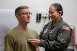 Military doctor uses a stethoscope on a service member.