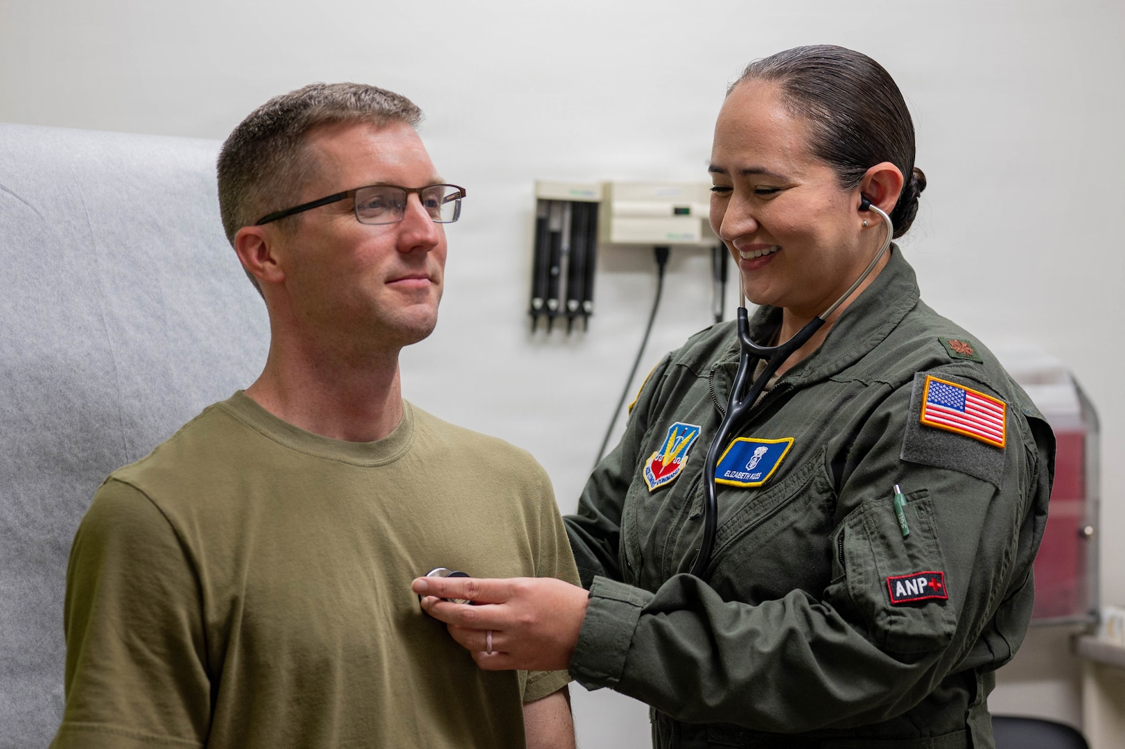 Military doctor uses a stethoscope on a service member.