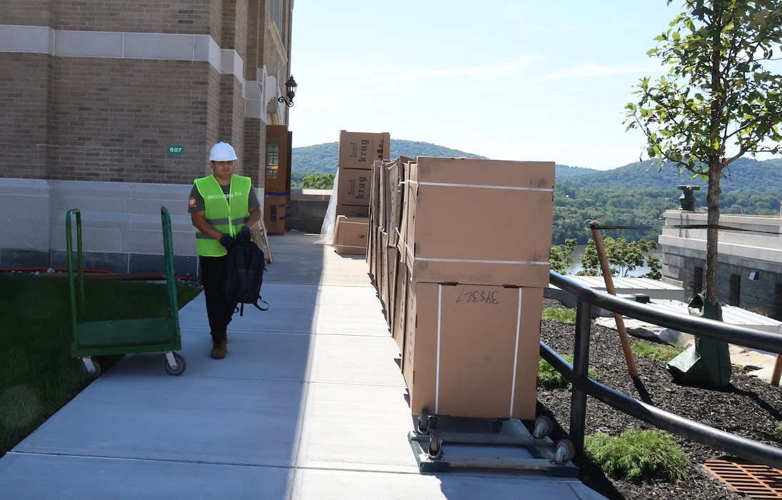 A construction worker in a hard hat and yellow vest prepares to move boxes.