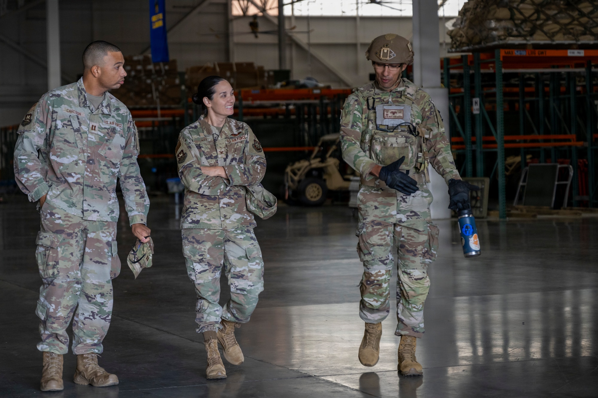 Three people walk and talk in a warehouse.