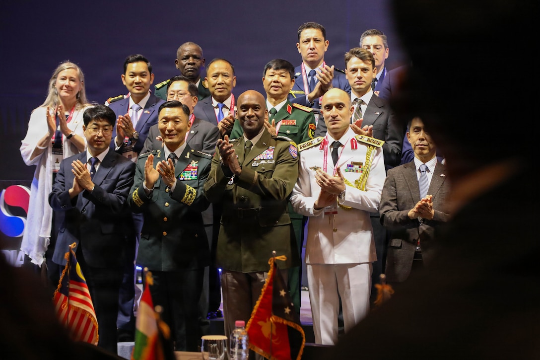 U.S. Army Gen. Xavier T. Brunson and South Korea Gen. Kim Sung-min stand with other leaders and applaud at the conclusion of the Seoul Defense Dialogue opening ceremony in Seoul on Sept. 8, 2026. Gen Brunson third from the left and Gen Kim second from the left. Several officials in suits and military uniforms stand alongside them, and a photographer captures the moment. The scene reflects an international defense forum focused on cooperation and shared challenges.