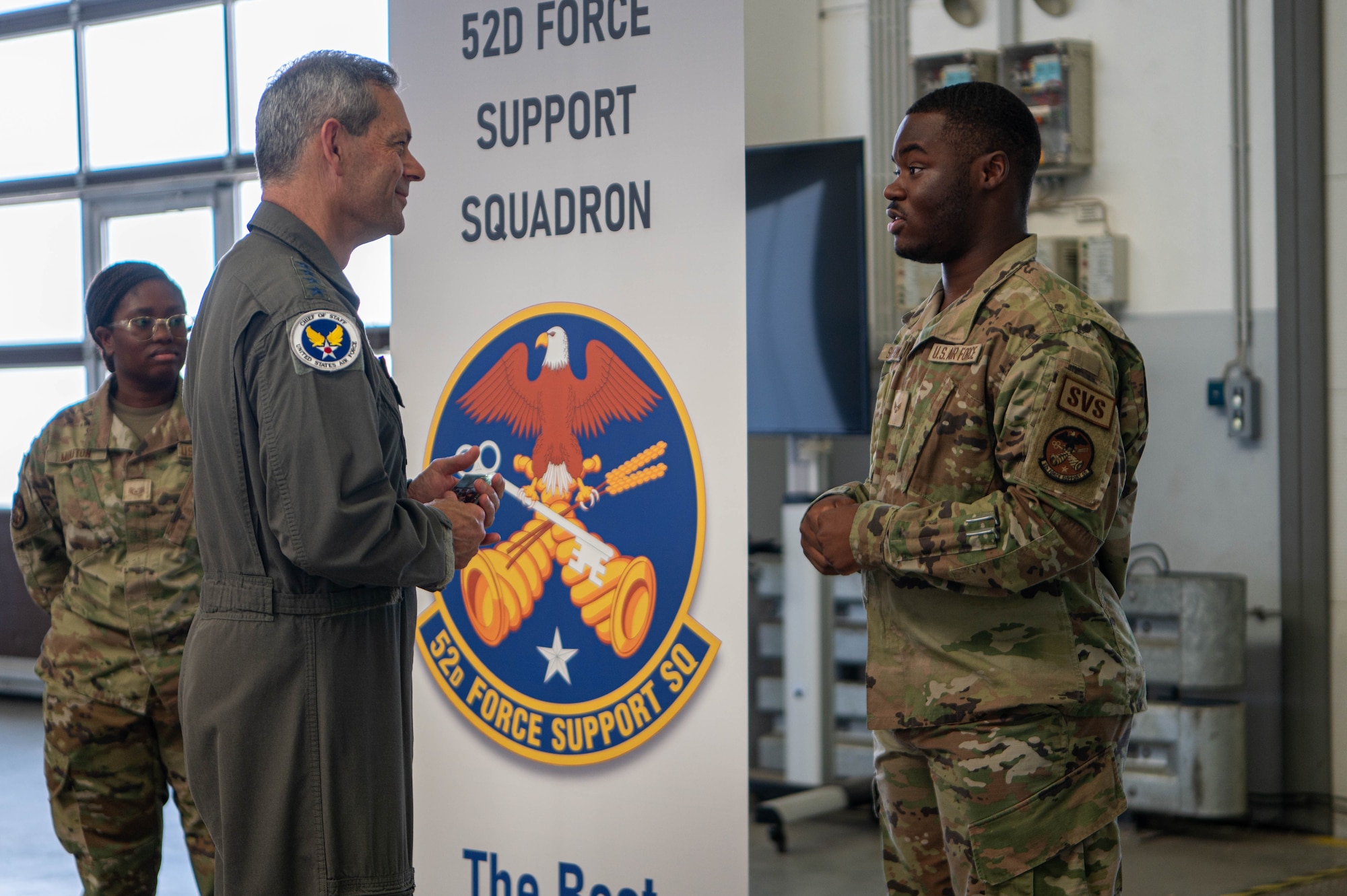 U.S. Air Force Senior Airman Tahjay Sherman, 52nd Force Support Squadron services journeyman, briefs Air Force Chief of Staff Gen. Ken Wilsbach on flight kitchen operations during a base visit.