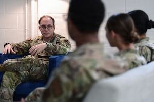 A man in a U.S. Air Force uniform speaks to fellow Airmen.