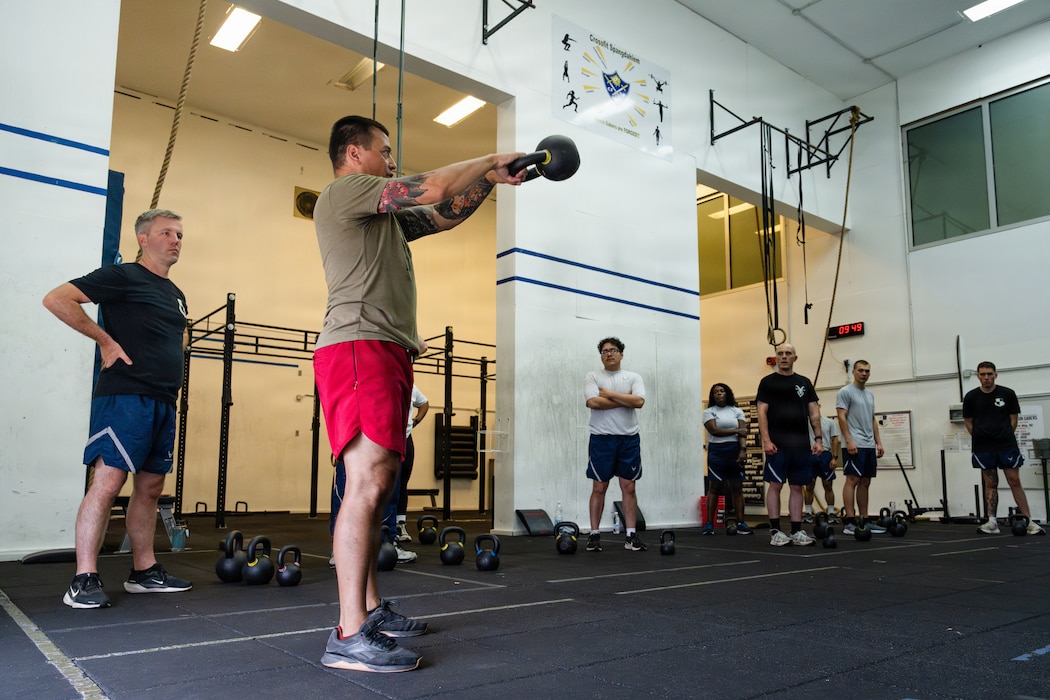 Craig Descoteaux, second from left, an operational support team strength and conditioning coach, instructs a kettlebell class during Saber Fitness Day.