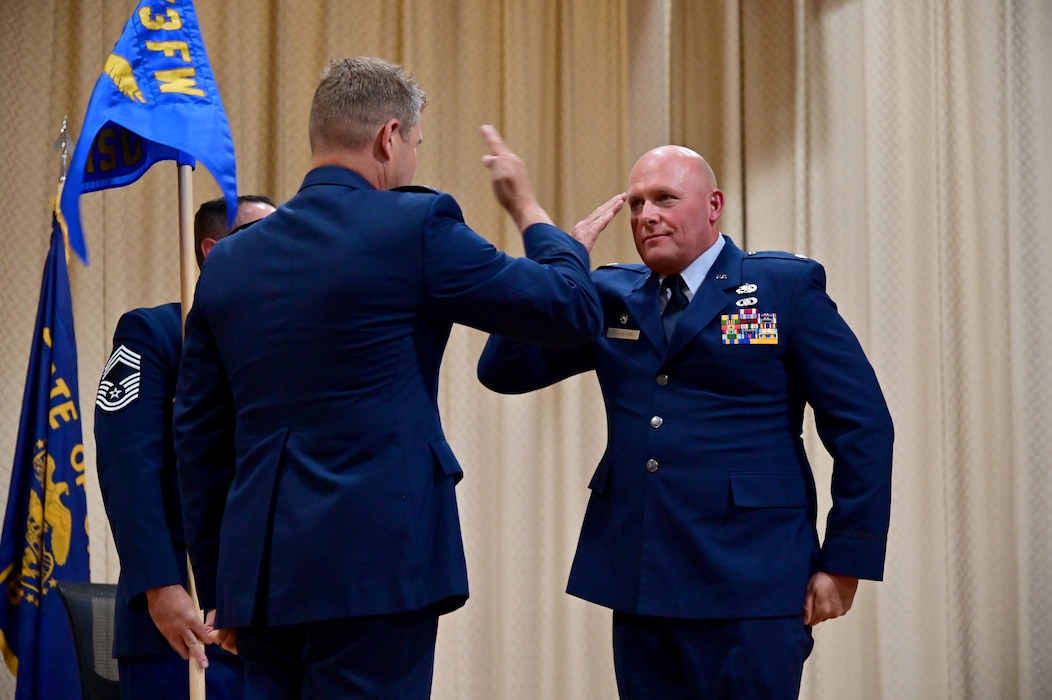 Two uniformed people salute each other