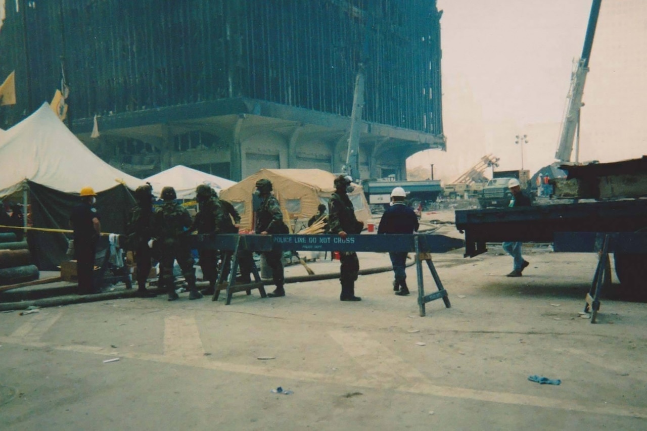 Six people in camouflage military  uniforms set up wooden barriers in a city.
