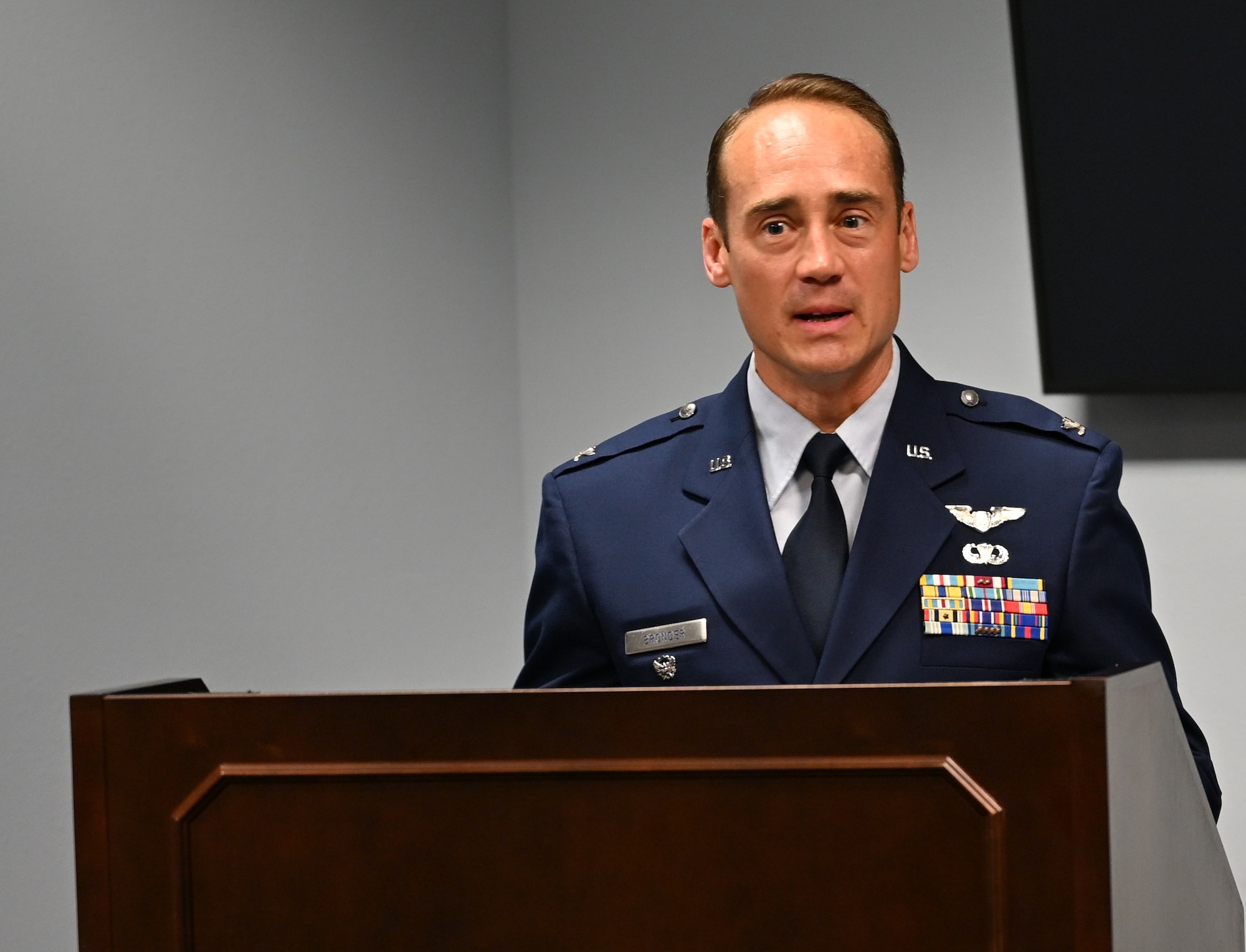 A man in Air Force dress uniform stands at a podium