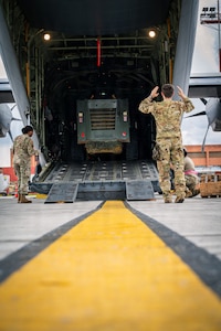 U.S. Air Force Airmen, assigned to the 374th Airlift Wing, direct life-saving equipment.