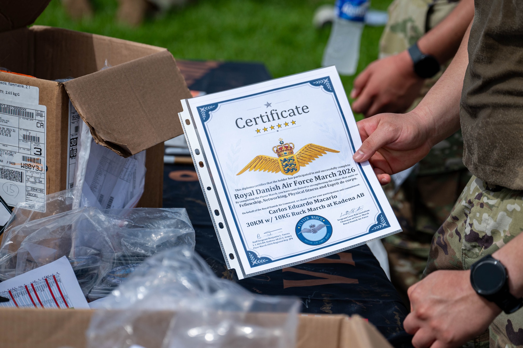 A U.S. service member receives a certificate after participating in the Royal Danish Air Force Flyver March at Kadena Air Base, Japan, Aug. 29, 2026. Participants were required to carry a ruck weighing at least 23 pounds throughout the 20-kilometer march. (U.S. Air Force photo by Airman 1st Class Nathaniel Jackson)