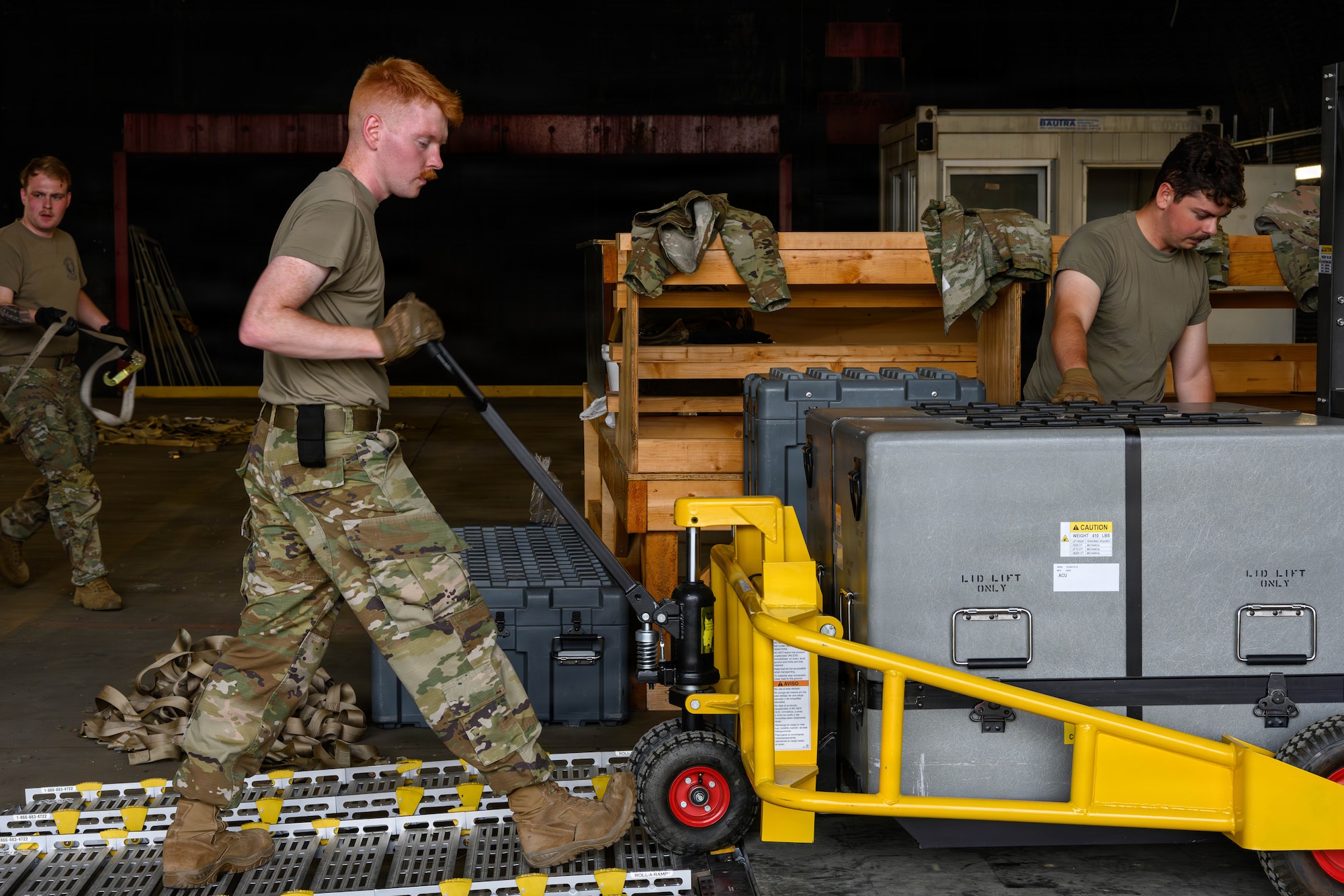 A U.S. Air Force Airman uses a pallet jack to unload equipment off a pallet.