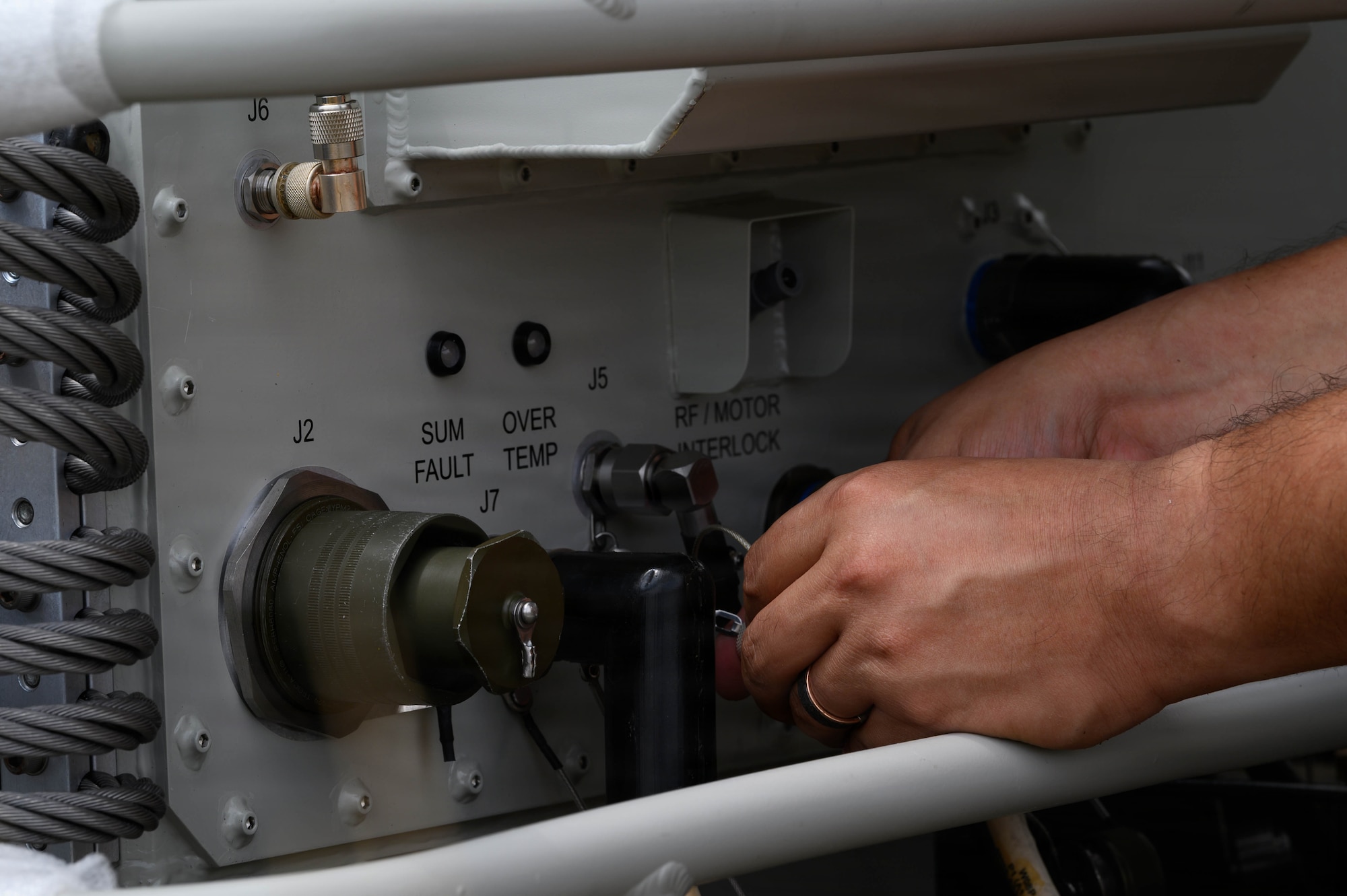 A U.S. Air Force Airman hooks up cables to a satellite.